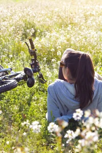 Jeune femme avec un vélo étendue sur l'herbe.