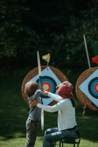 Enfant qui tire à l'arc sur une cible posée sur une botte de paille.